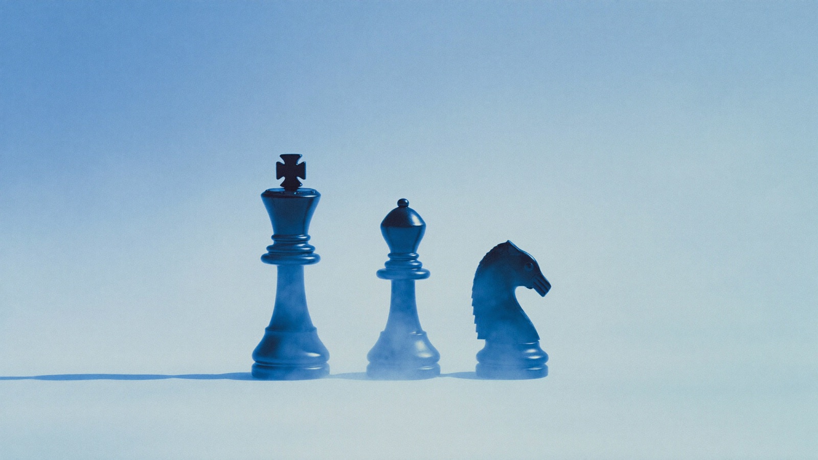 Three dark navy chess pieces in a row on a pale blue surface